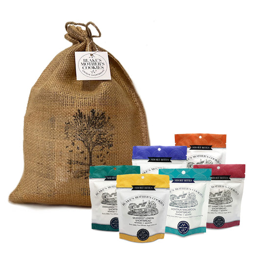 A burlap stringed bag with a stamped autumn tree and six 2.2 oz. Short Bites flavors in front. 