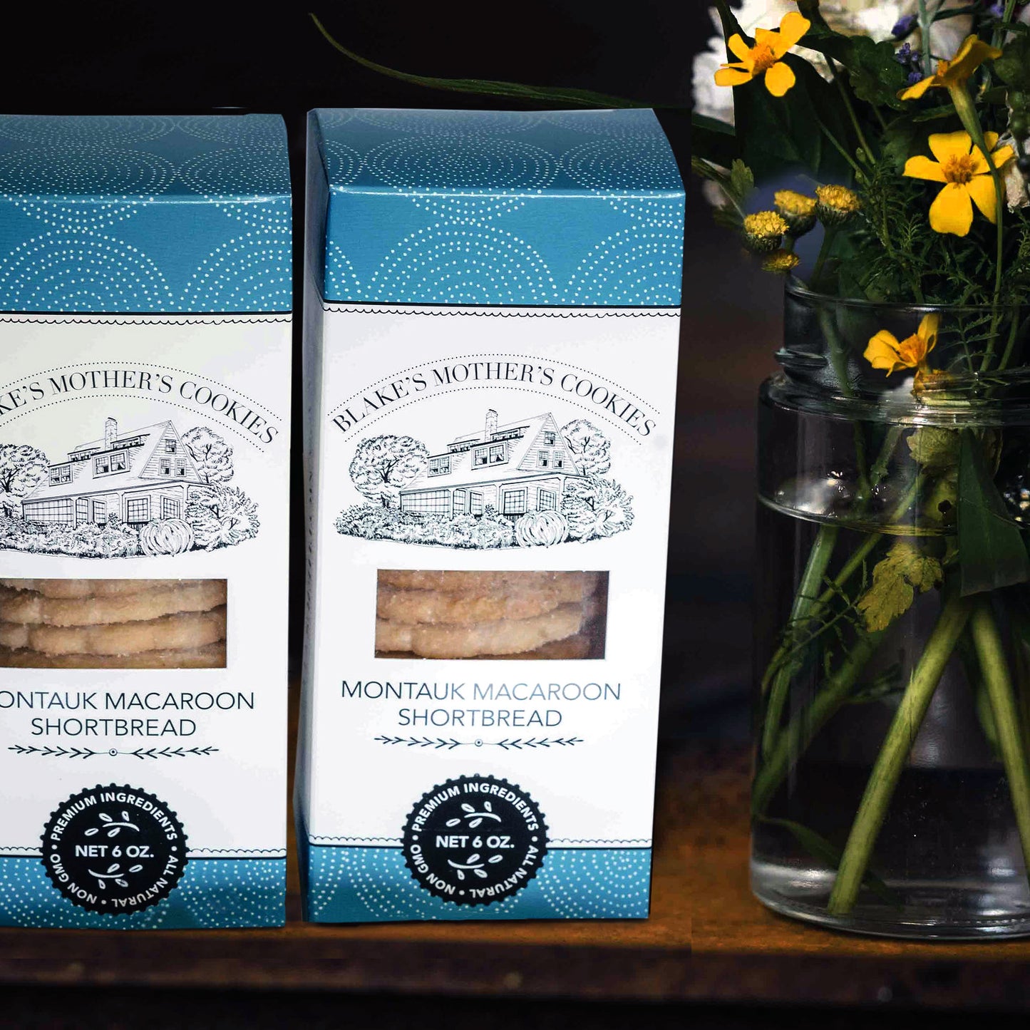 Two boxes of Blake's Mother's Cookies Montauk Macaroon Shortbread cookies next to a vase of country flowers