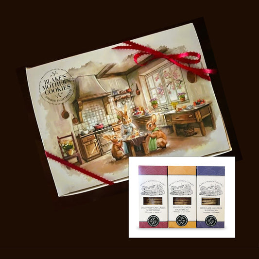 A delightful ribbon-tied gift box with a sketch of a family of bunnies enjoying shortbread and tea in their warm vintage kitchen A cherry tree is in full bloom outside the kitchen window. Inset are three 6 oz. Shortbread Cookie boxes in three favorite flavors.